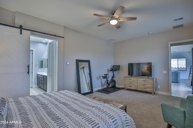 carpeted bedroom with a barn door, ceiling fan, and connected bathroom