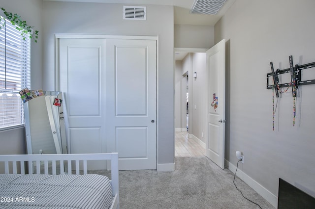 bedroom with multiple windows, a closet, and light colored carpet