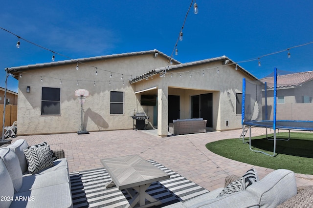 back of house featuring an outdoor living space, a trampoline, and a patio area