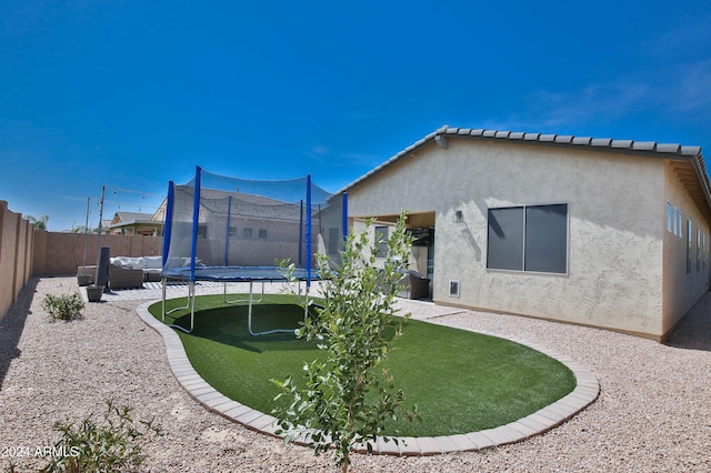 rear view of property featuring an outdoor hangout area and a trampoline