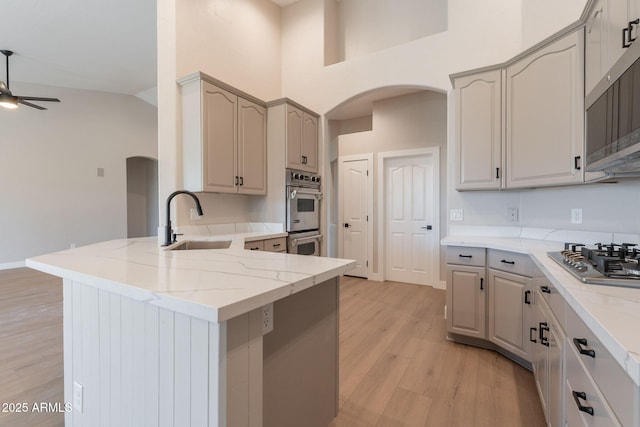 1062 N Robin Ln, Mesa, AZ 85213 - kitchen with arched walkways, a sink, appliances with stainless steel finishes, a ceiling fan, and a peninsula
