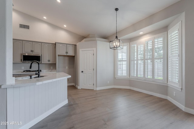 1062 N Robin Ln, Mesa, AZ 85213 - kitchen with stainless steel microwave, vaulted ceiling, light wood-style floors, light stone countertops, and baseboards
