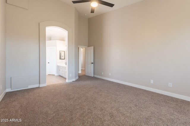 1062 N Robin Ln, Mesa, AZ 85213 - unfurnished bedroom with light carpet, arched walkways, baseboards, connected bathroom, and a ceiling fan