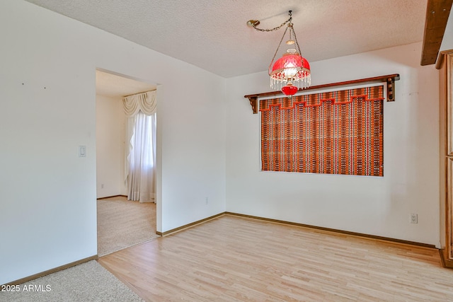 unfurnished room featuring baseboards, a textured ceiling, and wood finished floors