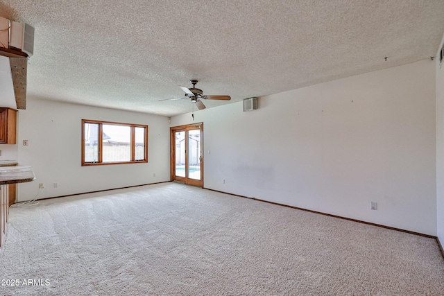 unfurnished living room with visible vents, a textured ceiling, baseboards, light colored carpet, and ceiling fan