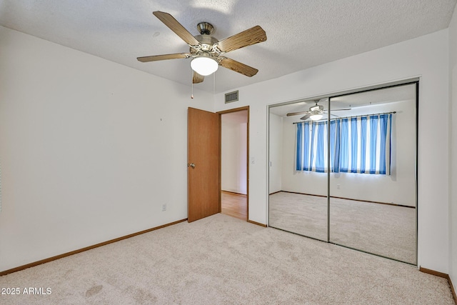 unfurnished bedroom featuring visible vents, a textured ceiling, a closet, carpet floors, and ceiling fan