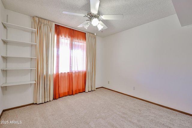 carpeted empty room featuring a textured ceiling, baseboards, and a ceiling fan