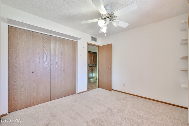unfurnished bedroom featuring visible vents, a ceiling fan, a textured ceiling, a closet, and carpet floors