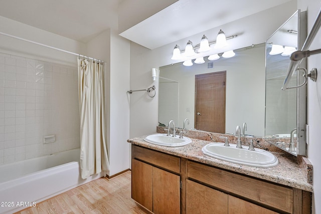 bathroom with double vanity, wood finished floors, shower / tub combo with curtain, and a sink