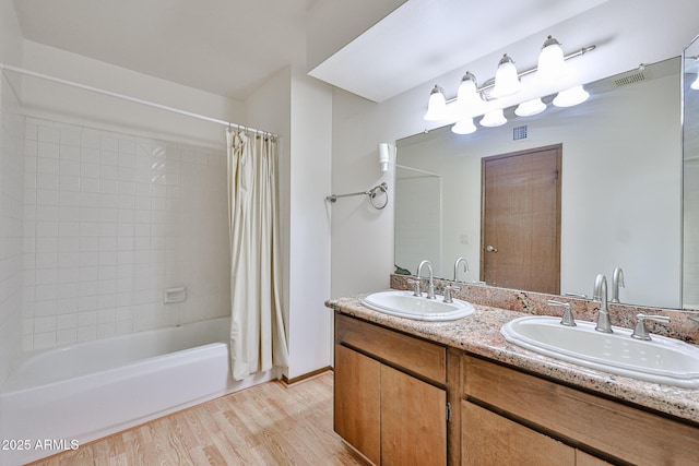 full bath featuring visible vents, wood finished floors, shower / bath combo, and a sink