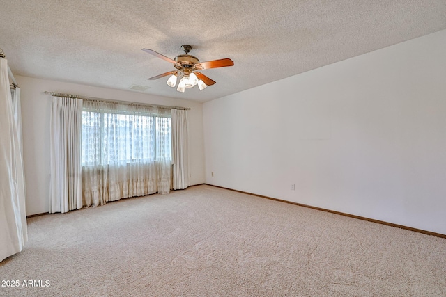 carpeted spare room with visible vents, a textured ceiling, baseboards, and ceiling fan