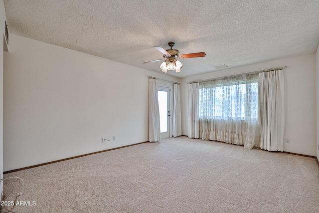 carpeted spare room featuring visible vents, a textured ceiling, baseboards, and a ceiling fan