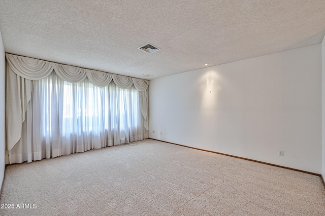carpeted empty room featuring baseboards, visible vents, and a textured ceiling