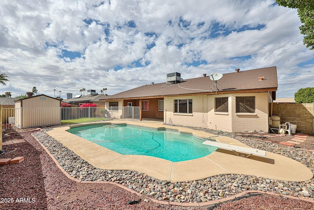 view of swimming pool with an outbuilding, a fenced backyard, a shed, a fenced in pool, and a patio area
