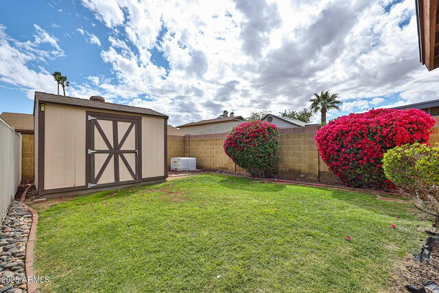 view of yard featuring an outbuilding, a fenced backyard, and a shed