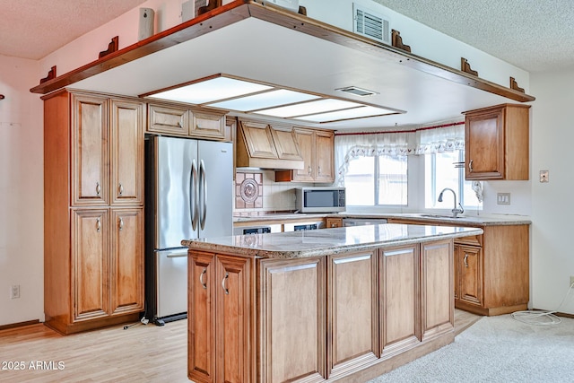 kitchen featuring premium range hood, visible vents, a center island, appliances with stainless steel finishes, and light stone countertops