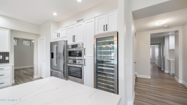 kitchen featuring white cabinetry, light stone countertops, stainless steel appliances, and beverage cooler