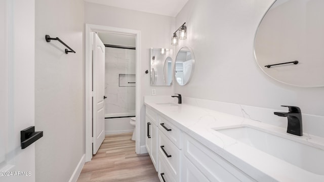 full bathroom with vanity, tiled shower / bath combo, toilet, and hardwood / wood-style flooring