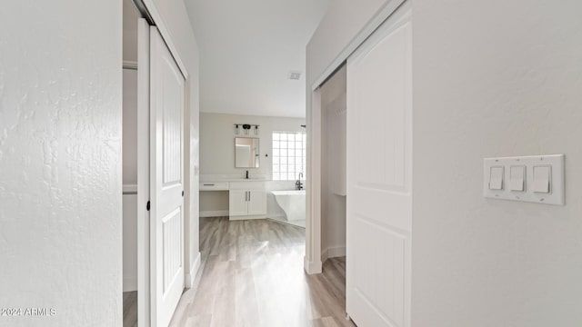 corridor featuring light hardwood / wood-style floors and sink