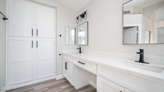 bathroom with vanity, hardwood / wood-style flooring, and vaulted ceiling