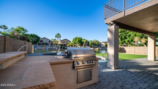 view of patio / terrace featuring a water view, area for grilling, and a fenced in pool