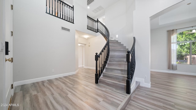 staircase with a towering ceiling and hardwood / wood-style floors