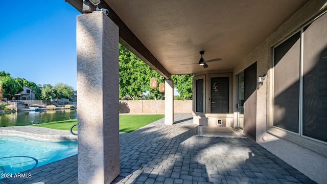 view of patio / terrace featuring a water view, ceiling fan, and a fenced in pool