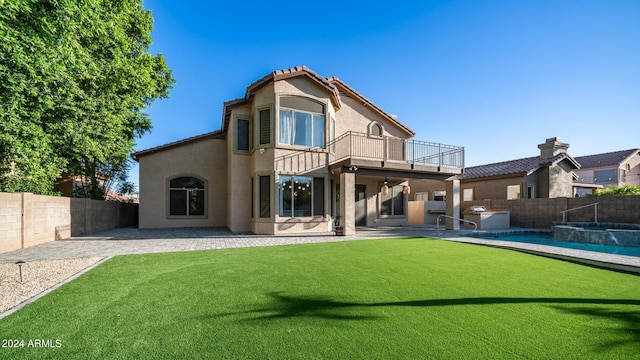 back of property featuring a balcony, a lawn, a patio area, and exterior kitchen