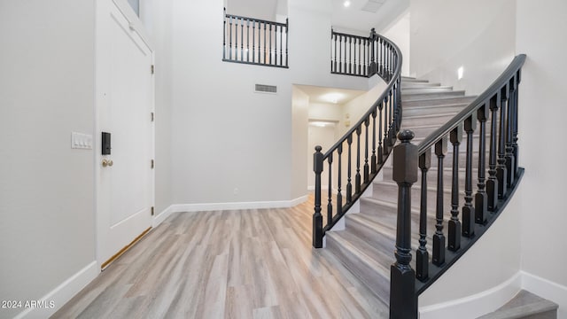 stairs featuring wood-type flooring and a towering ceiling