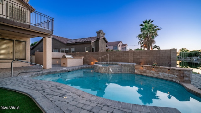 pool at dusk with an in ground hot tub, area for grilling, a patio area, and a water view