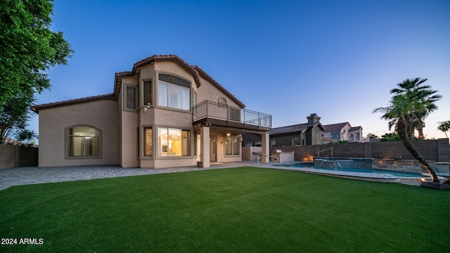 back house at dusk featuring pool water feature, a balcony, a yard, and a fenced in pool