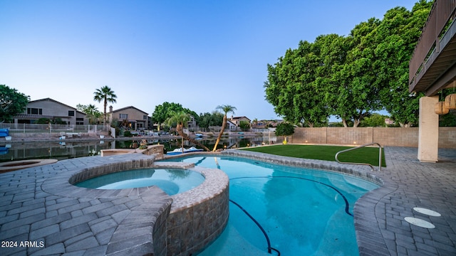 view of pool featuring a lawn, an in ground hot tub, and a water view