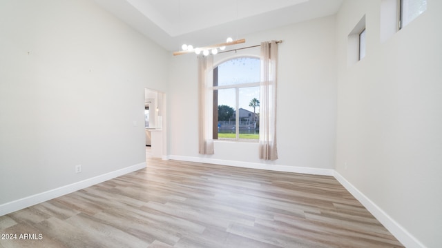 unfurnished room with high vaulted ceiling and light wood-type flooring