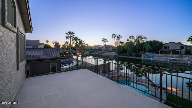 patio terrace at dusk with a balcony and a water view