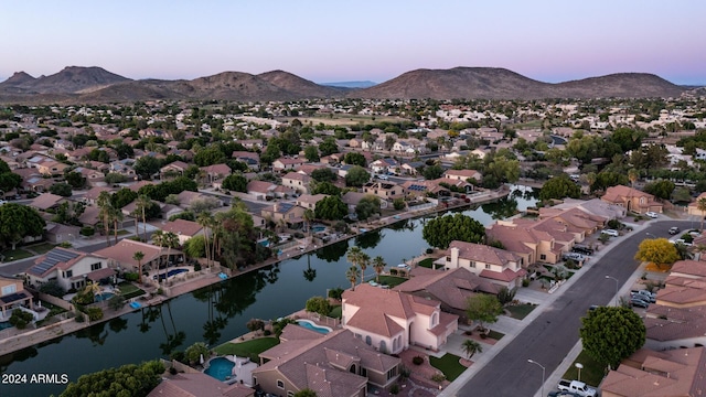 aerial view at dusk featuring a water and mountain view