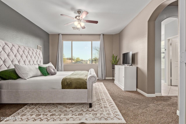 bedroom featuring arched walkways, carpet flooring, a ceiling fan, visible vents, and baseboards