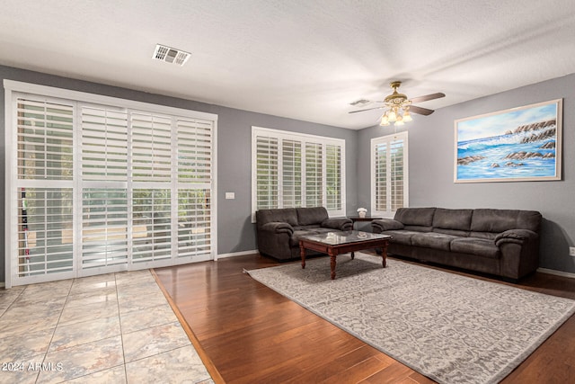 living room with a wealth of natural light, ceiling fan, hardwood / wood-style flooring, and a textured ceiling