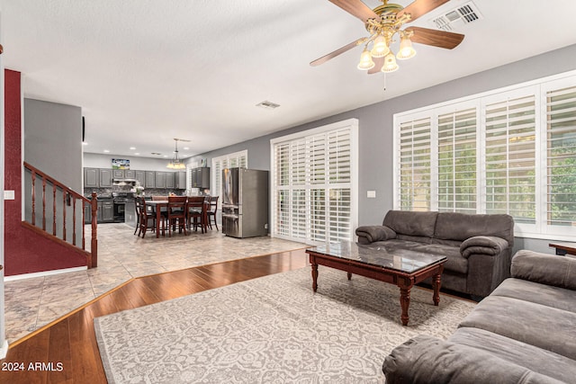 living room with light wood-type flooring, a textured ceiling, and ceiling fan