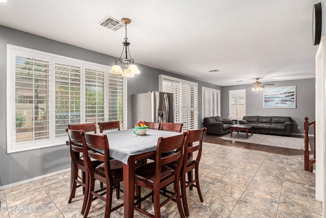 dining space with ceiling fan with notable chandelier and a wealth of natural light