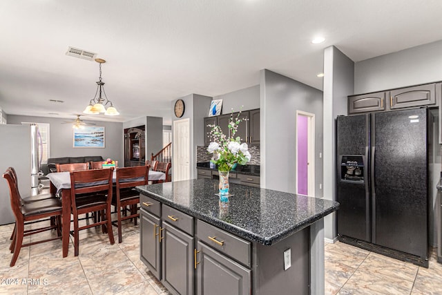 kitchen featuring dark stone countertops, stainless steel refrigerator, a kitchen island, ceiling fan, and black refrigerator with ice dispenser