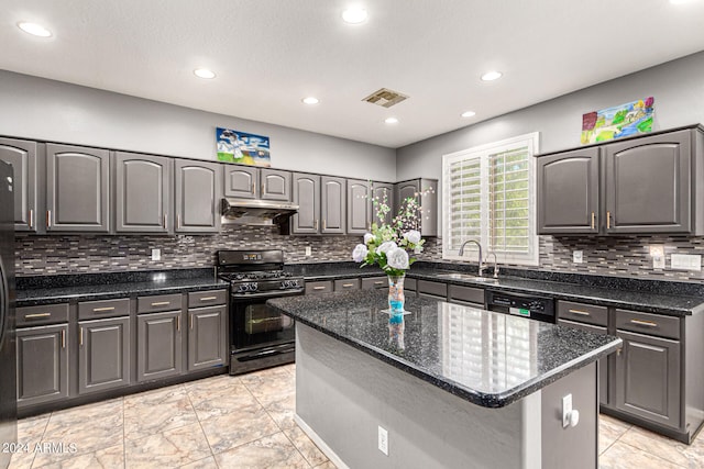 kitchen with a kitchen island, black appliances, sink, decorative backsplash, and dark stone countertops