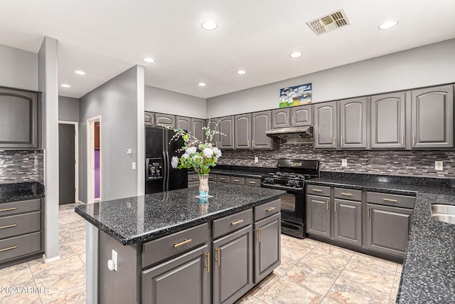 kitchen with gray cabinets, black appliances, dark stone counters, a kitchen island, and decorative backsplash