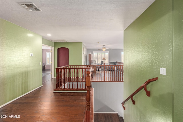 hall featuring a textured ceiling and dark hardwood / wood-style floors