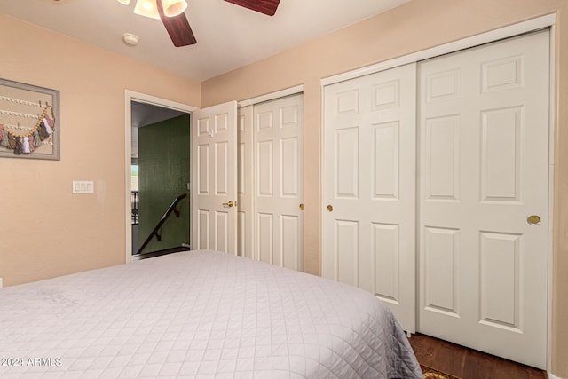 bedroom with dark hardwood / wood-style flooring, two closets, and ceiling fan