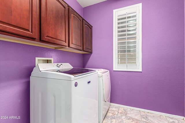 clothes washing area featuring separate washer and dryer, cabinets, and light tile patterned floors