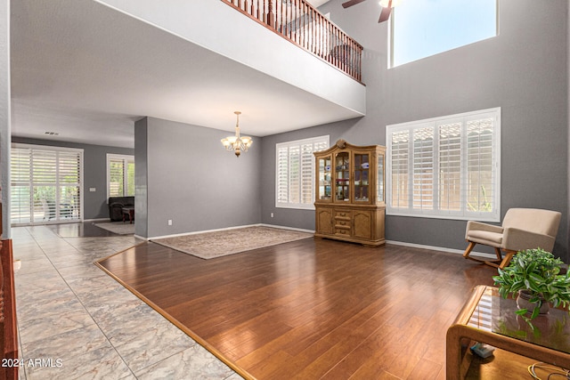 unfurnished living room with ceiling fan with notable chandelier and hardwood / wood-style flooring