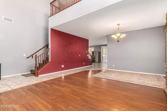 unfurnished living room featuring light wood-type flooring and a notable chandelier