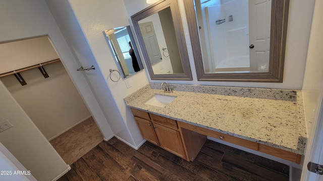 full bathroom featuring vanity, a walk in closet, and wood finished floors