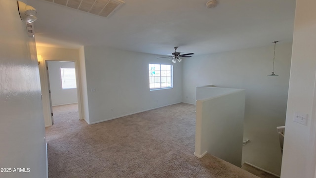 carpeted empty room with ceiling fan, baseboards, and visible vents