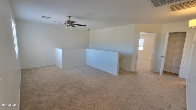 spare room with ceiling fan, light carpet, baseboards, and visible vents